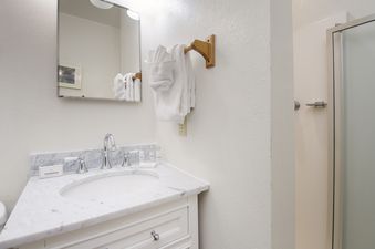 The bathroom in Hideaway Village Ladora 3 features a well-lit vanity with a white marble countertop, a chrome faucet, and a clean white sink, offering essential toiletries and a fresh towel rack.