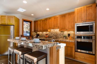 The kitchen in Abode at the Crux features granite countertops and stainless steel appliances.