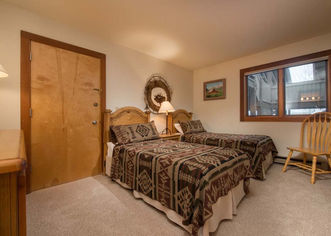 Cozy bedroom in Nez Perce C4 featuring two twin beds with Southwestern-patterned bedding and wooden furniture.