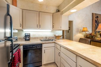 A well-equipped kitchen with light-colored cabinetry, stainless steel appliances, and a breakfast bar.