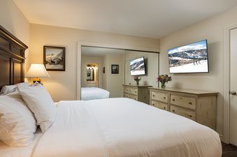 The bedroom in Enzian 217 features a comfortable bed and a mounted flat screen TV.