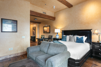 Grand Lodge Studio 205 features a bedroom with a large bed, pillows, and a comfortable couch.