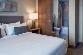The Grand Colorado on Peak 8 Suite Residence features a luxurious bedroom with a comfortable bed, stylish furnishings, and a view of the adjoining bathroom.