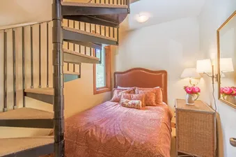 Cozy bedroom at Lynx at the Terraces with a spiral staircase and warm lighting.