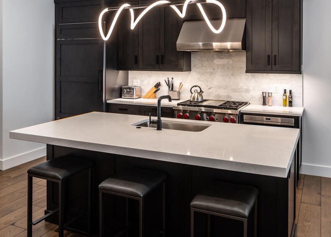 Moonlight Basin 9 Wildwood features a modern kitchen with a large island with seating, stainless steel appliances, and sleek black cabinetry.