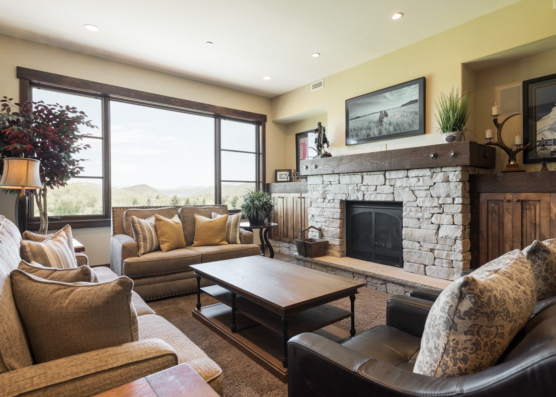 The spacious living area of Silver Star 1303 features comfortable sofas, a stone fireplace, and large windows with mountain views.