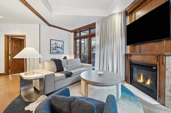The Aspen 03B living room is spacious with a large couch, a fireplace, and a flat screen TV mounted above it.