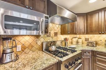 A close-up view of the kitchen in The Chateaux Four Bedroom Residence, highlighting the stainless steel microwave and granite countertops.