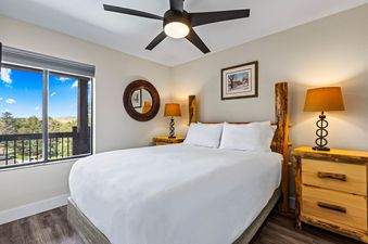 A cozy bedroom in Snowcrest 302 featuring a rustic log bed and a large window with a scenic view.