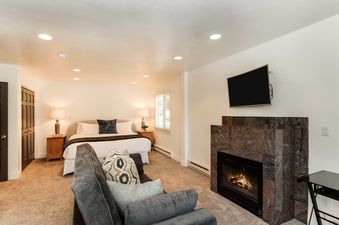 A spacious king suite at Dolomite Villas 1 with a comfortable king-sized bed, a modern fireplace, and a flat-screen TV.