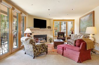 The comfortable and bright living room at 411 Beaver Creek Lodge featuring a fireplace, seating area, and large windows.
