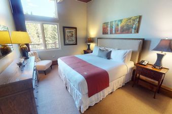 A hotel room with a large bed, a dresser, and a nightstand.