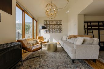 The living area of the Telluride Lodge Retreat features comfortable seating, a fireplace, and large windows with mountain views.
