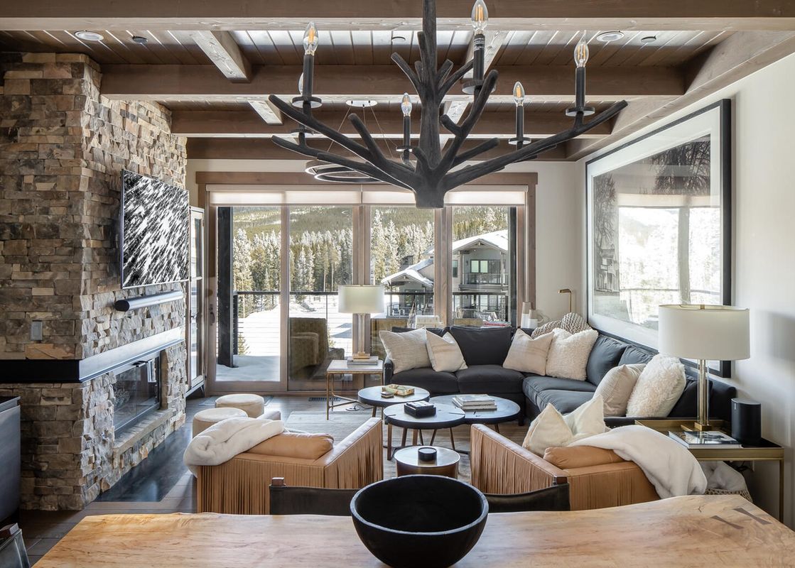 Moonlight Basin 10 Wildwood living room features a fireplace, large windows with views of the mountains, a sectional sofa, and a coffee table.