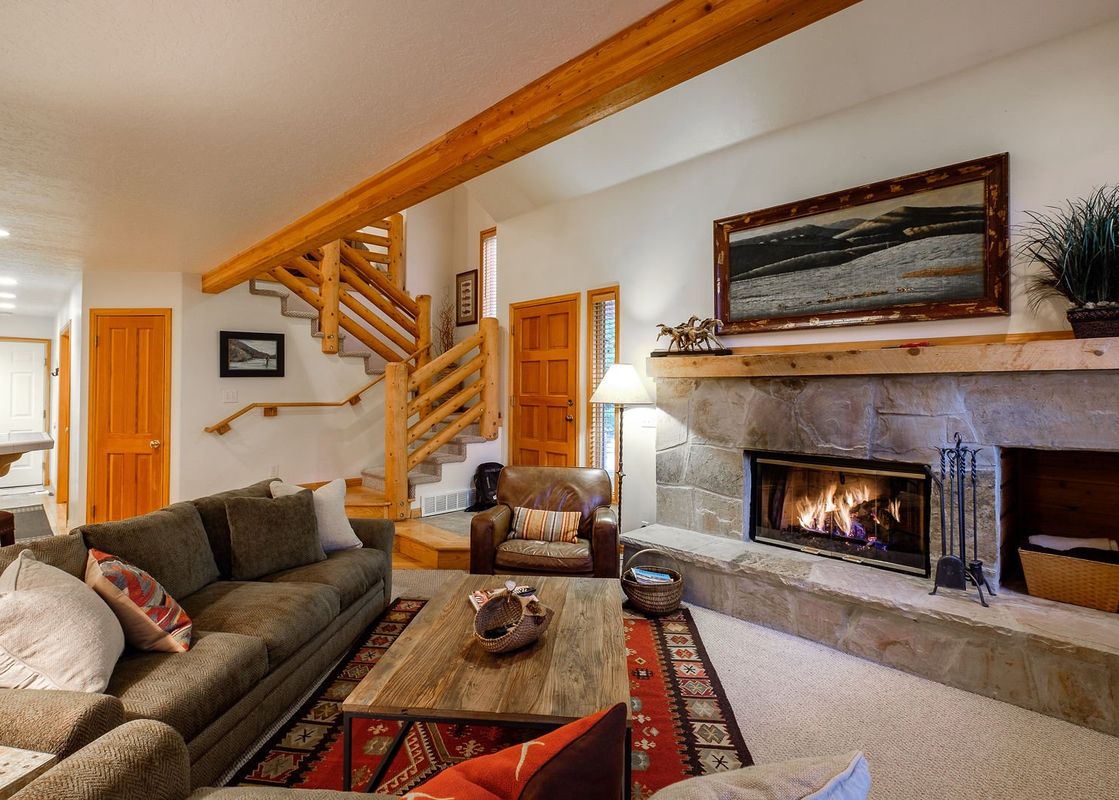 A cozy living room in Deer Lake Village Abode features a stone fireplace and comfortable seating.