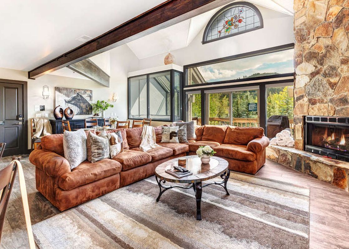 The inviting living room at Abode at Queen Esther features a stone fireplace and comfortable seating.