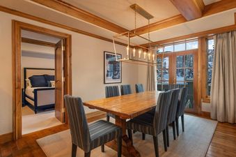 A formal dining room, which includes a wooden dining table, a rectangular golden chandelier, and multiple chairs.