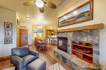A comfortable living area in EagleRidge Lodge 311 featuring a leather armchair next to a large stone fireplace and a dining set in the background.