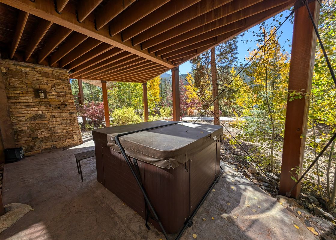 The outdoor hot tub at Keystone Prospectors Home 669 is nestled under a wooden deck, offering a view of vibrant autumn foliage.