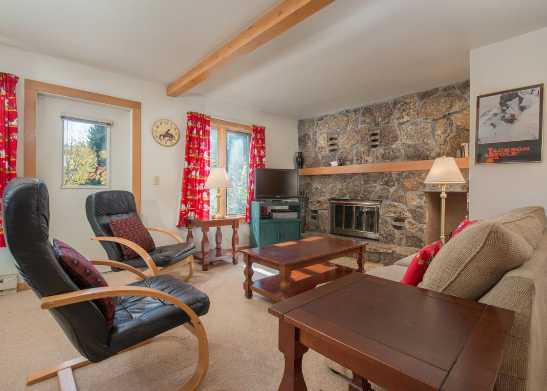 Cozy living room in Rendezvous A2 featuring a large stone fireplace, comfortable armchairs, and a warm, inviting atmosphere.