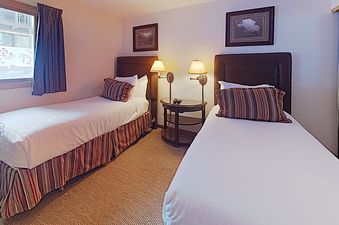A cozy bedroom in Timberline Two Bedroom B2E featuring two twin beds, a wooden nightstand, and framed artwork.
