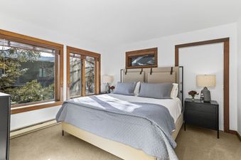 Well-lit master bedroom with a queen bed and scenic window views at Sundance Jackson Hole.