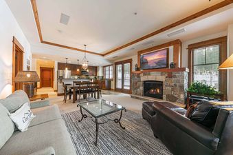 Big Horn Lodge 202 living room with fireplace and large TV, comfy couches, dining table, and view of the mountains