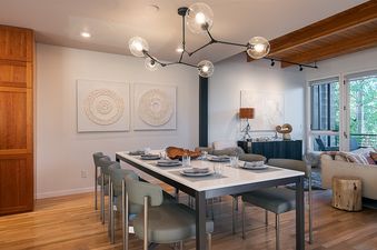 Modern dining table with olive-green chairs under a molecular chandelier at Hawks View Chalet.