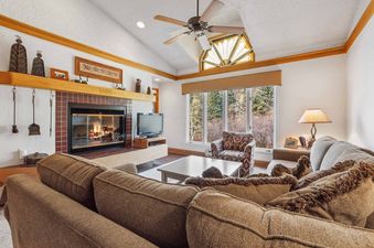 The living room at The Charter D4105, featuring a fireplace, comfortable seating, and a large window with an outdoor view.