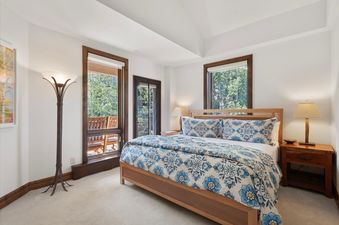 A beautifully decorated bedroom in Chamonix 50 with a king bed, wood-trimmed windows, and forest views.