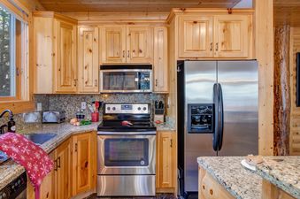 The kitchen in Black Bear 231 features wooden cabinets, stainless steel appliances, and granite countertops.