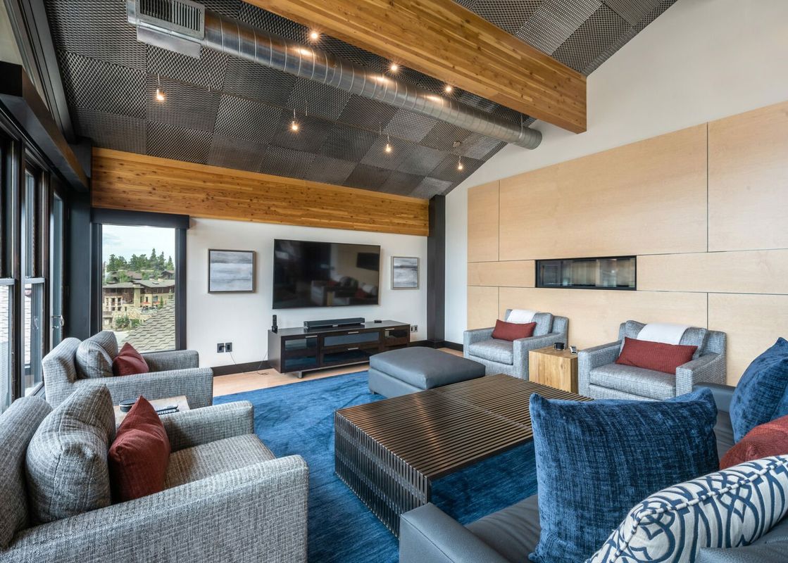 The living room in Royal Plaza Penthouse features a fireplace, a large TV, plush furniture, and a great view from the large windows.