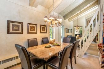A formal dining room in Villa Valhalla 2 Bedroom Loft Gold Unit 7 with a marble table and leather chairs under a chandelier.