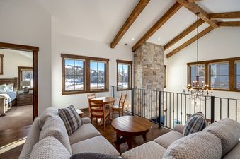 A cozy loft living area at The Bear and Moose Lodge with vaulted wood-beam ceilings and snowy mountain views outside.