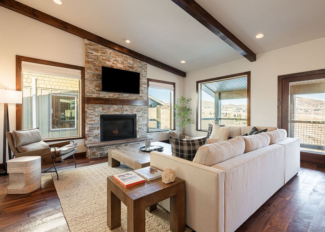 Cozy living room at Deer Valley East Basecamp featuring a stone fireplace, large sectional, and scenic window views.