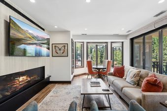 Inviting living room at 421 Beaver Creek Lodge featuring a comfortable sofa, warm fireplace, large TV, and a cozy dining nook.