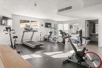 A bright and spacious fitness room with various exercise machines.