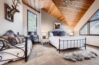 The bedroom in Ullr Haus features a spacious bed, comfortable bedding, and a wall-mounted deer head decoration.