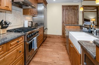 A fully equipped gourmet kitchen in Arrabelle 460 with wooden cabinetry, granite countertops, and stainless steel appliances.