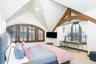 A bedroom with a large bed, a window with a view of snow-covered mountains, and a desk with a chair.