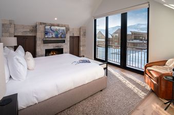 A cozy bedroom at Spotted Saddle Lodge features a fireplace and a view of the snowy landscape.