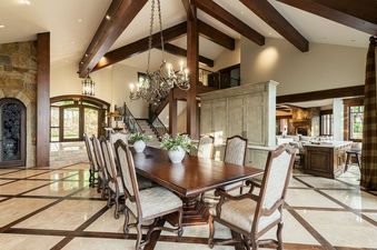 A luxurious dining area with a long wood table under a vaulted beamed ceiling at Park City Colony at Elite Elevation.