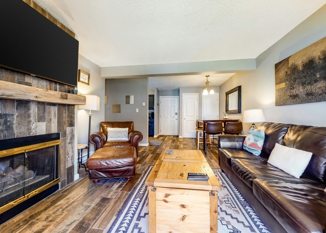 A living room with a fireplace, brown leather furniture, and a wooden coffee table