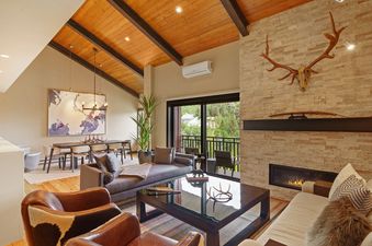 A living room with a large window, a fireplace, and a large leather couch