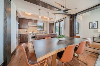 The dining area in Lumiere 2 Bedroom Suite features a large table with seating for six, modern light fixtures, and a view of the mountains.