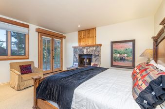 Cozy bedroom in Summit Cabin See Forever Cabin 103 with a large wooden bed, stone fireplace, and rustic decor.