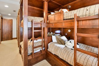 A cozy bunk room in Arrowleaf Lodge 302 featuring custom-built wooden bunk beds with plaid bedding and decorative pillows, offering a comfortable and rustic ambiance.