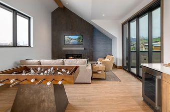 An aerial view of the Wildhorse Preserve 6 Bedroom open-plan living and kitchen area, featuring modern appliances, a fireplace, a flat-screen TV, and a unique foosball-style lighting fixture.