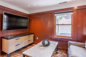 A modern entertainment area with a large flat-screen TV, a light wood media console, and a contemporary coffee table with a decorative sculpture.