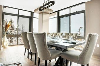 An elegant dining room in Lowell 301B with a large table set for eight guests, featuring expansive windows overlooking a snowy winter landscape.